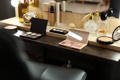 Makeup room. Cosmetic products and perfumes on wooden dressing table indoors