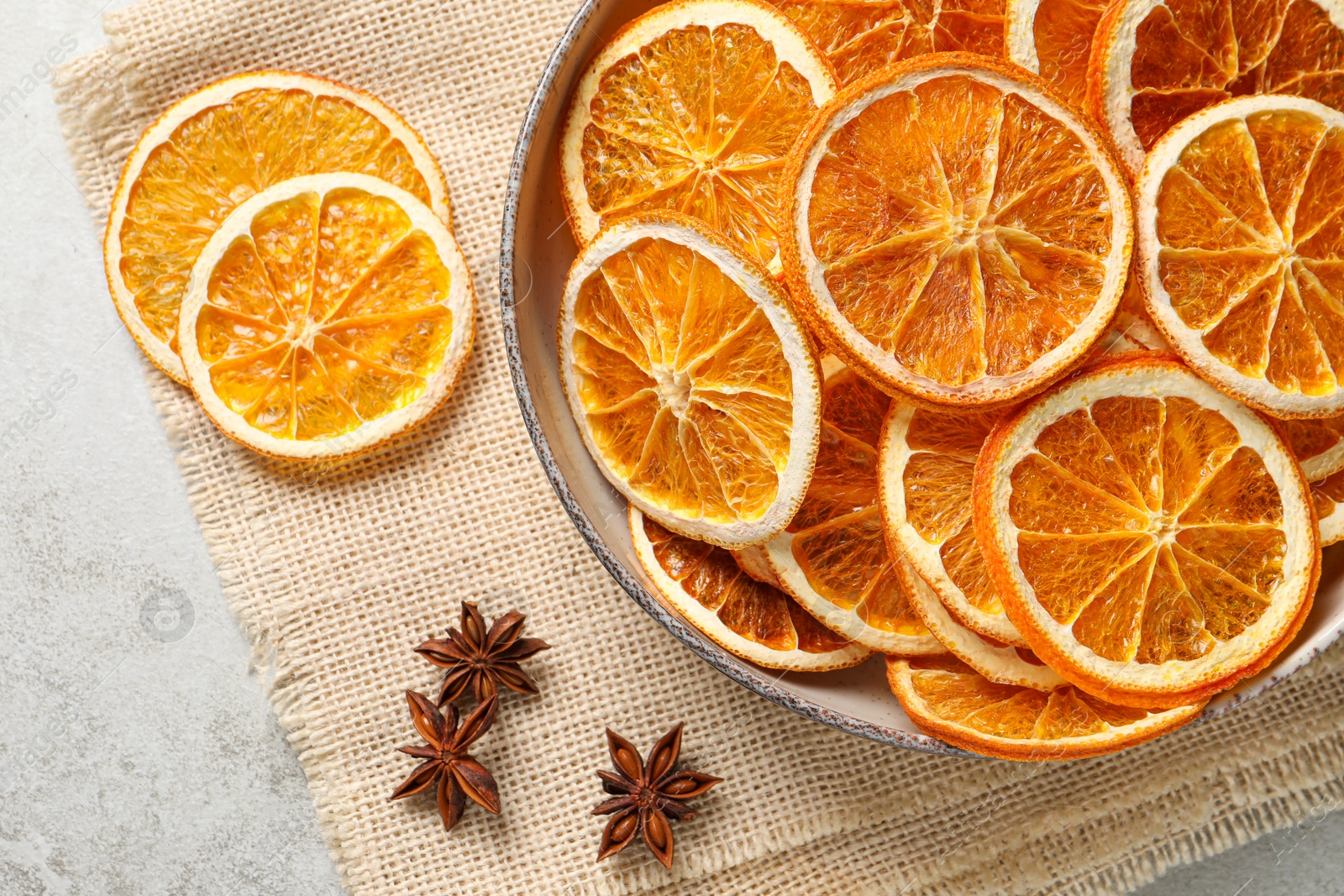 Photo of Dry orange slices and anise stars on light table, top view