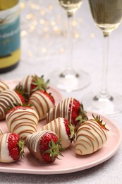 Delicious chocolate covered strawberries and sparkling wine on light table, closeup