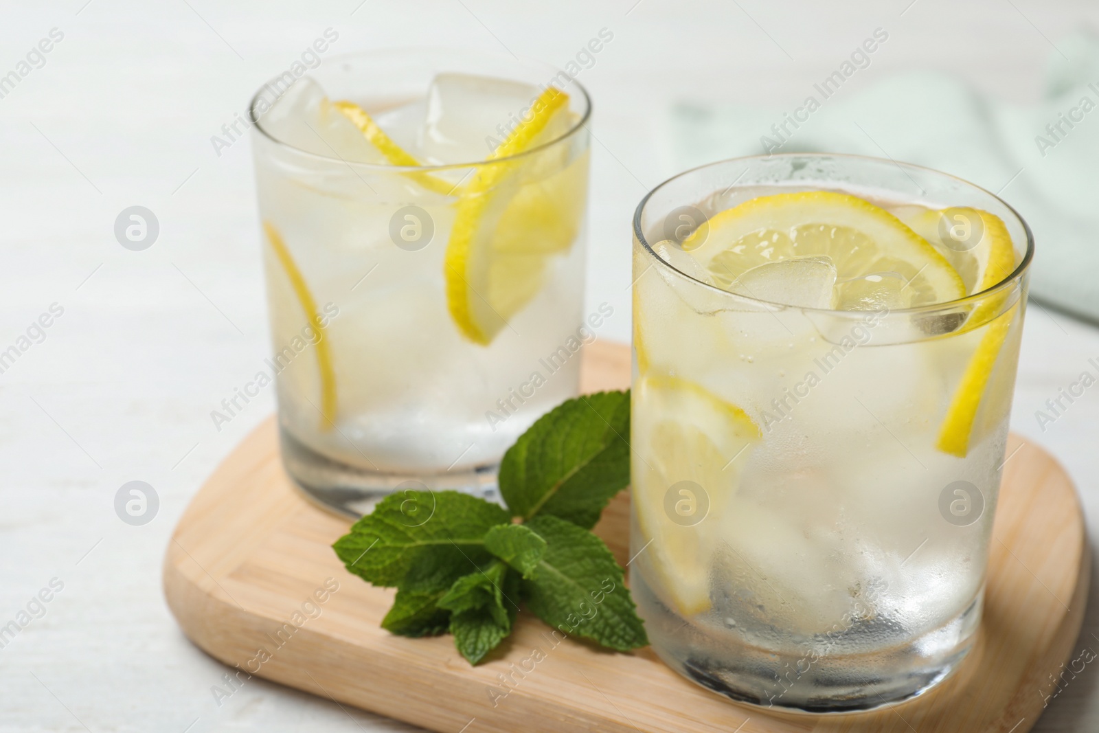 Photo of Glasses of cocktail with vodka, ice and lemon on white wooden table