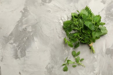 Photo of Bunch of fresh stinging nettles on light grey table, flat lay. Space for text
