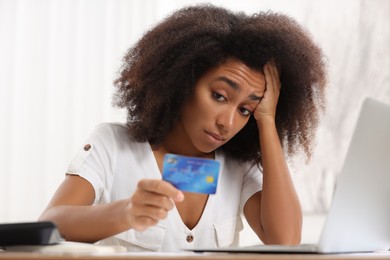 Photo of Confused woman with credit card planning budget indoors. Debt problem