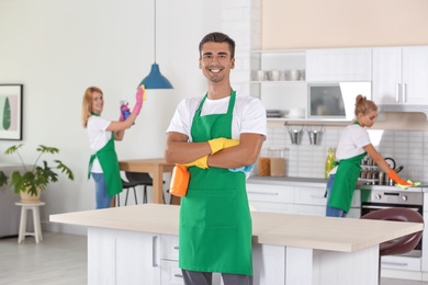 Photo of Team of professional janitors in uniform cleaning kitchen