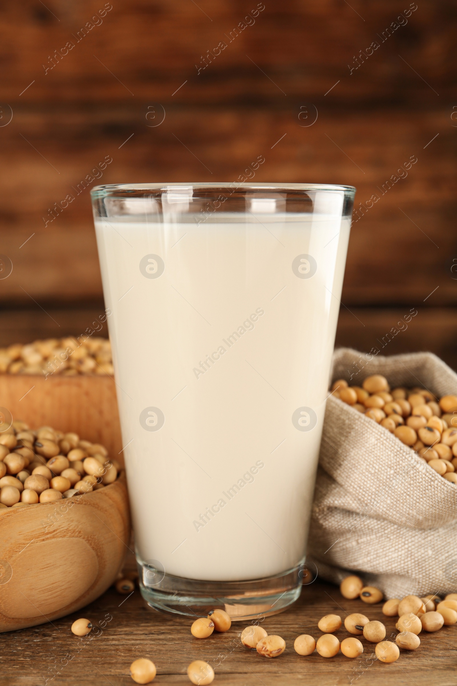 Photo of Glass with fresh soy milk and grains on wooden table