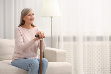 Photo of Mature woman with walking cane on sofa at home