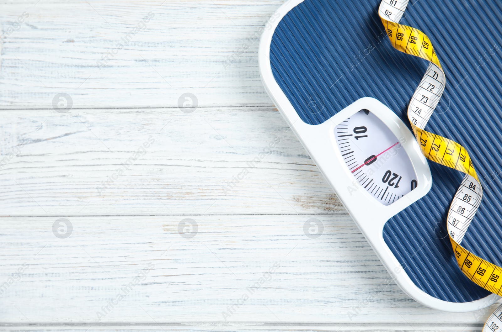 Photo of Scales and measuring tape on wooden background, top view with space for text. Weight loss