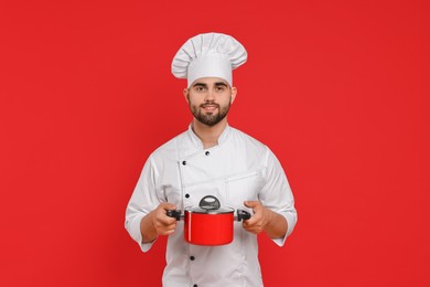 Photo of Professional chef with cooking pot on red background