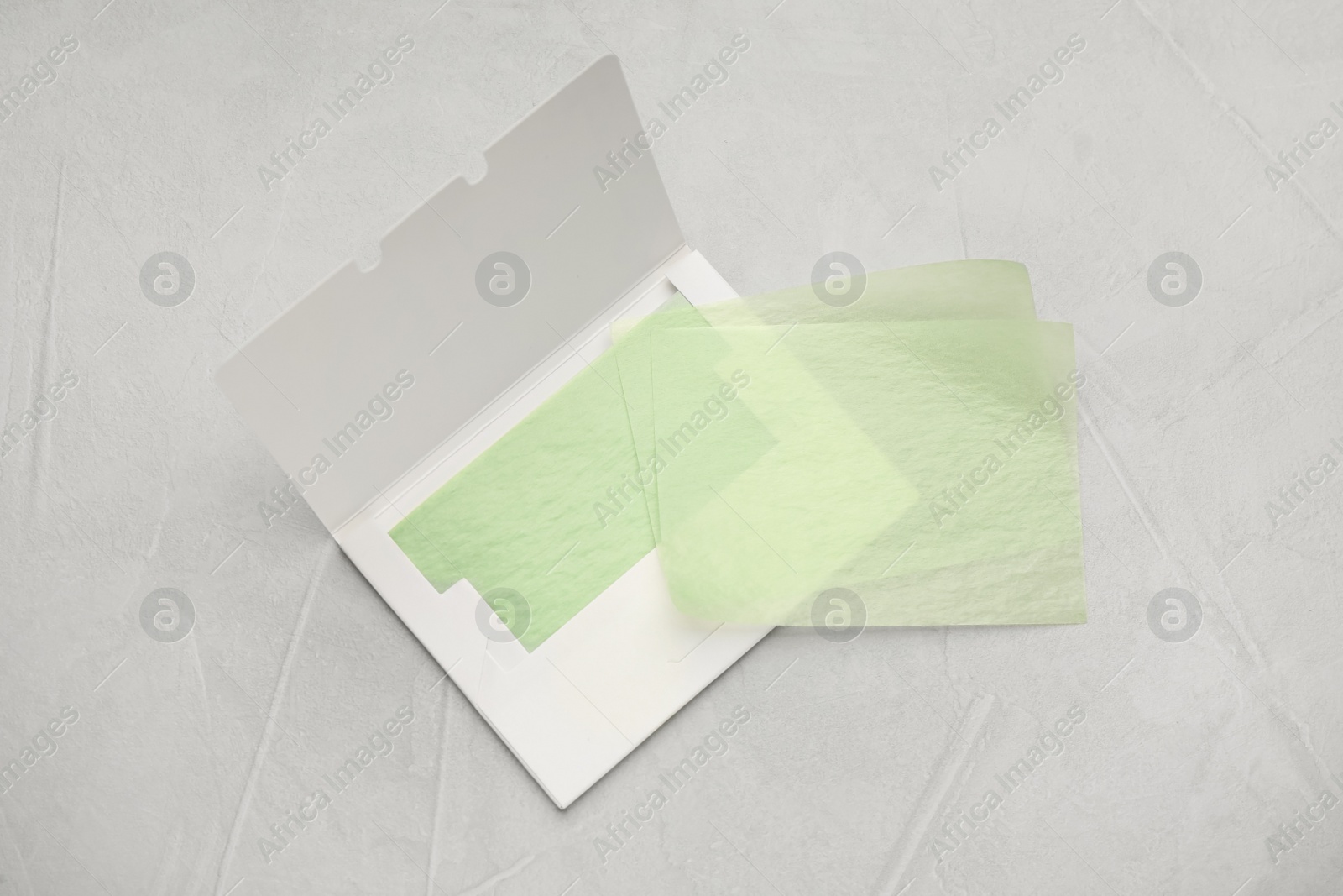 Photo of Facial oil blotting tissues on light grey background, flat lay. Mattifying wipes