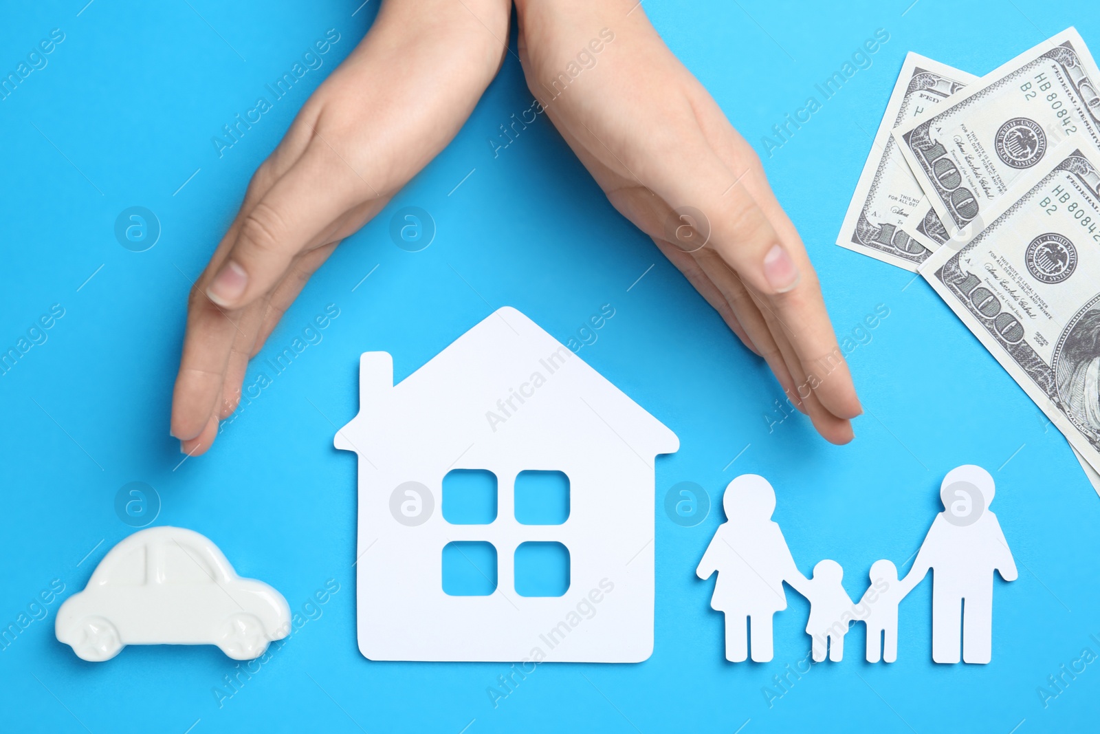 Photo of Woman holding hands over paper silhouettes of family, house and car on color background, top view. Life insurance concept