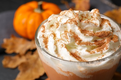Photo of Delicious pumpkin latte with whipped cream on table, closeup