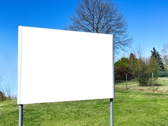 Photo of White blank signboard outdoors on sunny day. Mockup for design
