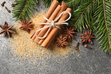 Photo of Different spices and fir branches on gray table, flat lay. Space for text