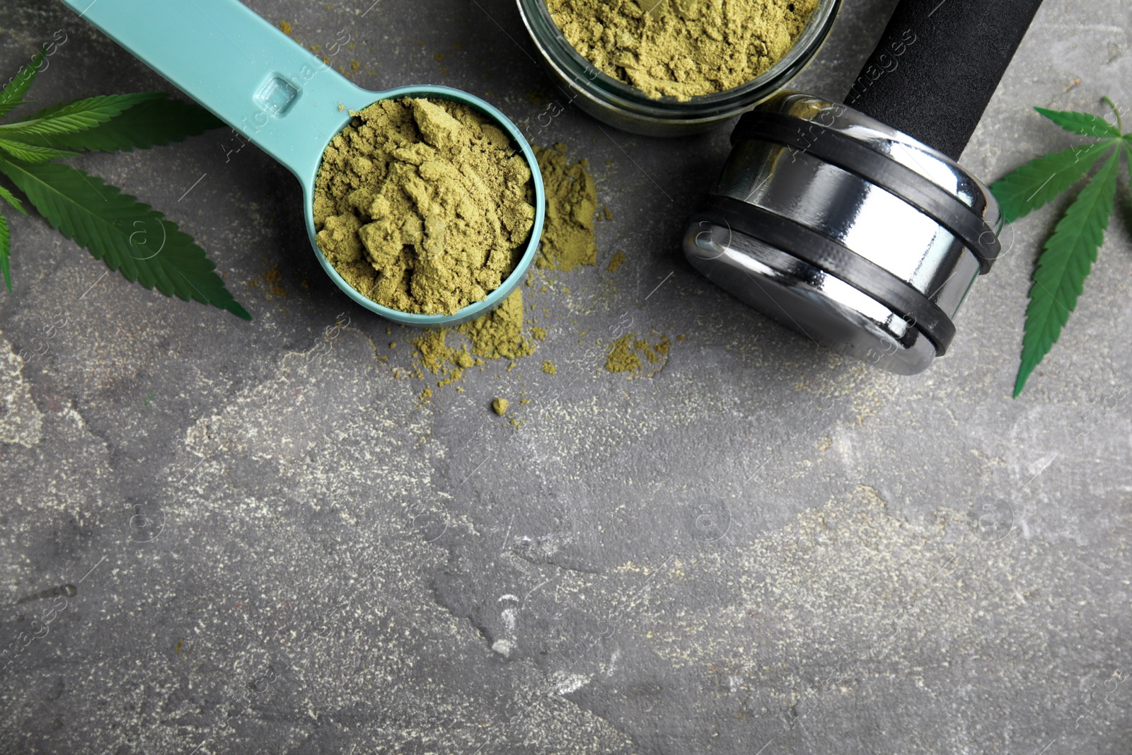 Photo of Hemp protein powder, fresh leaves and dumbbell on grey table, flat lay. Space for text