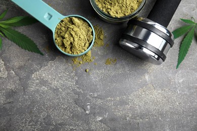 Photo of Hemp protein powder, fresh leaves and dumbbell on grey table, flat lay. Space for text