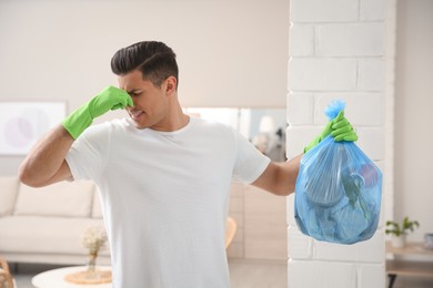 Photo of Man holding full garbage bag at home