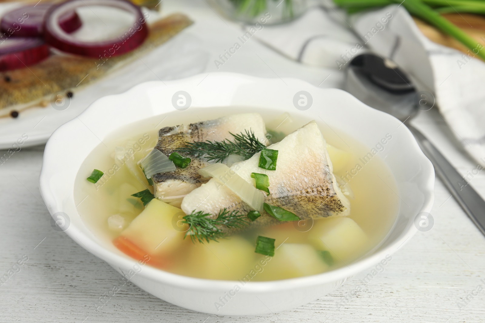 Photo of Delicious fish soup served on white wooden table, closeup