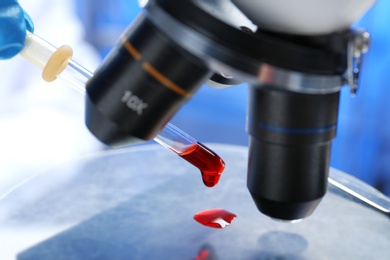 Photo of Laboratory worker running blood test using microscope, closeup. Research and analysis
