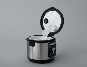 Photo of Modern electric multi cooker, parts and accessories on grey background