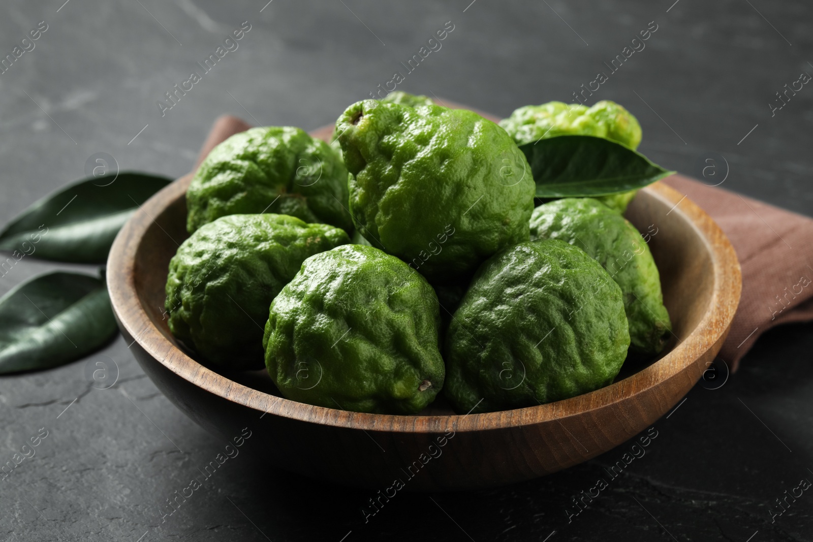 Photo of Fresh ripe bergamot fruits in bowl on black table