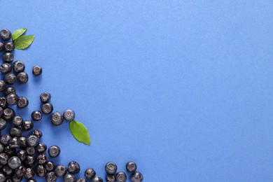 Ripe bilberries and leaves on blue background, flat lay. Space for text