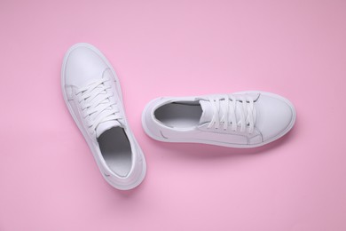 Photo of Pair of stylish white sneakers on pink background, top view