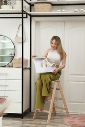 Photo of Woman with boots sitting on ladder indoors. Interior design