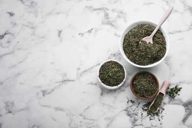 Photo of Bowls, spoon and scoop with dried thyme on white marble table, flat lay. Space for text