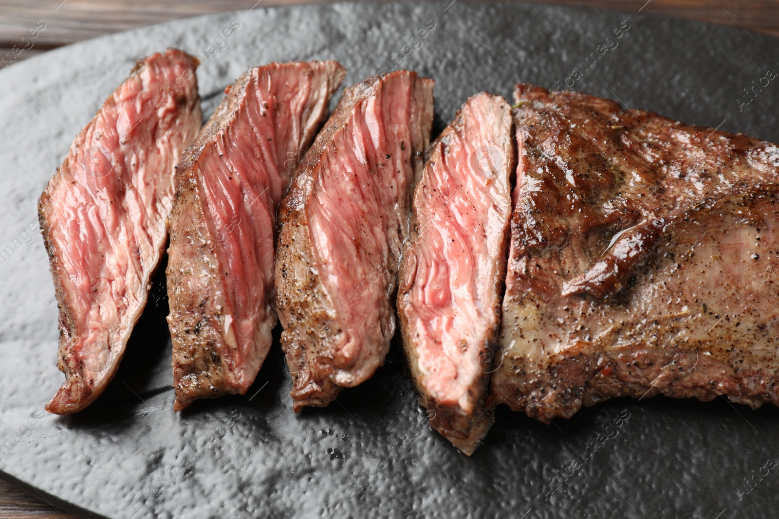 Photo of Pieces of delicious grilled beef meat on board, closeup