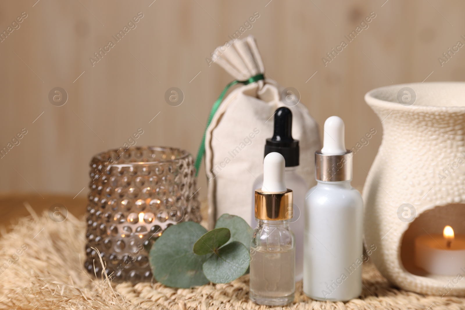 Photo of Different aromatherapy products, burning candles and eucalyptus leaves on table, closeup