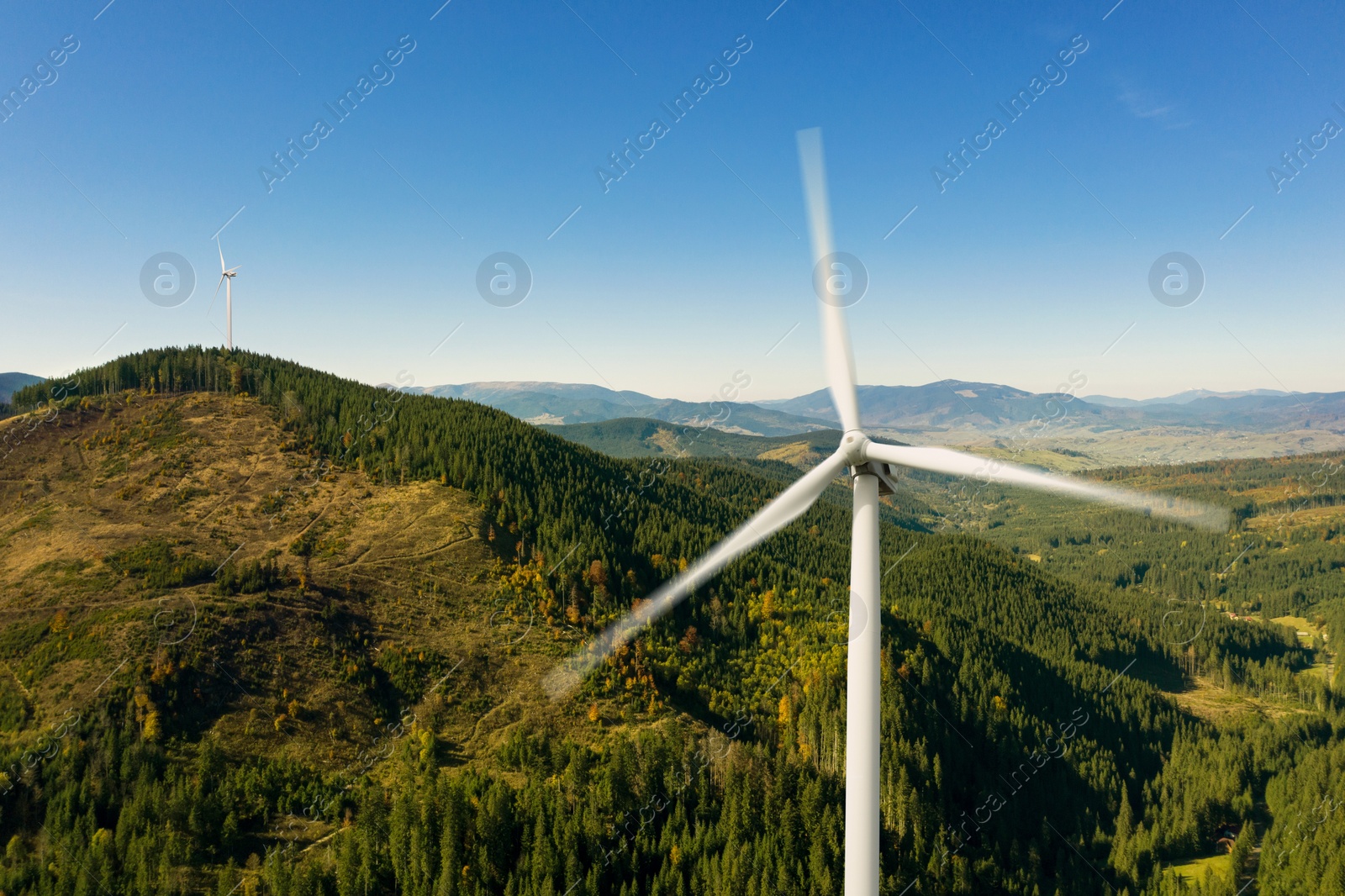 Image of Modern wind turbines in mountains on sunny day. Alternative energy source