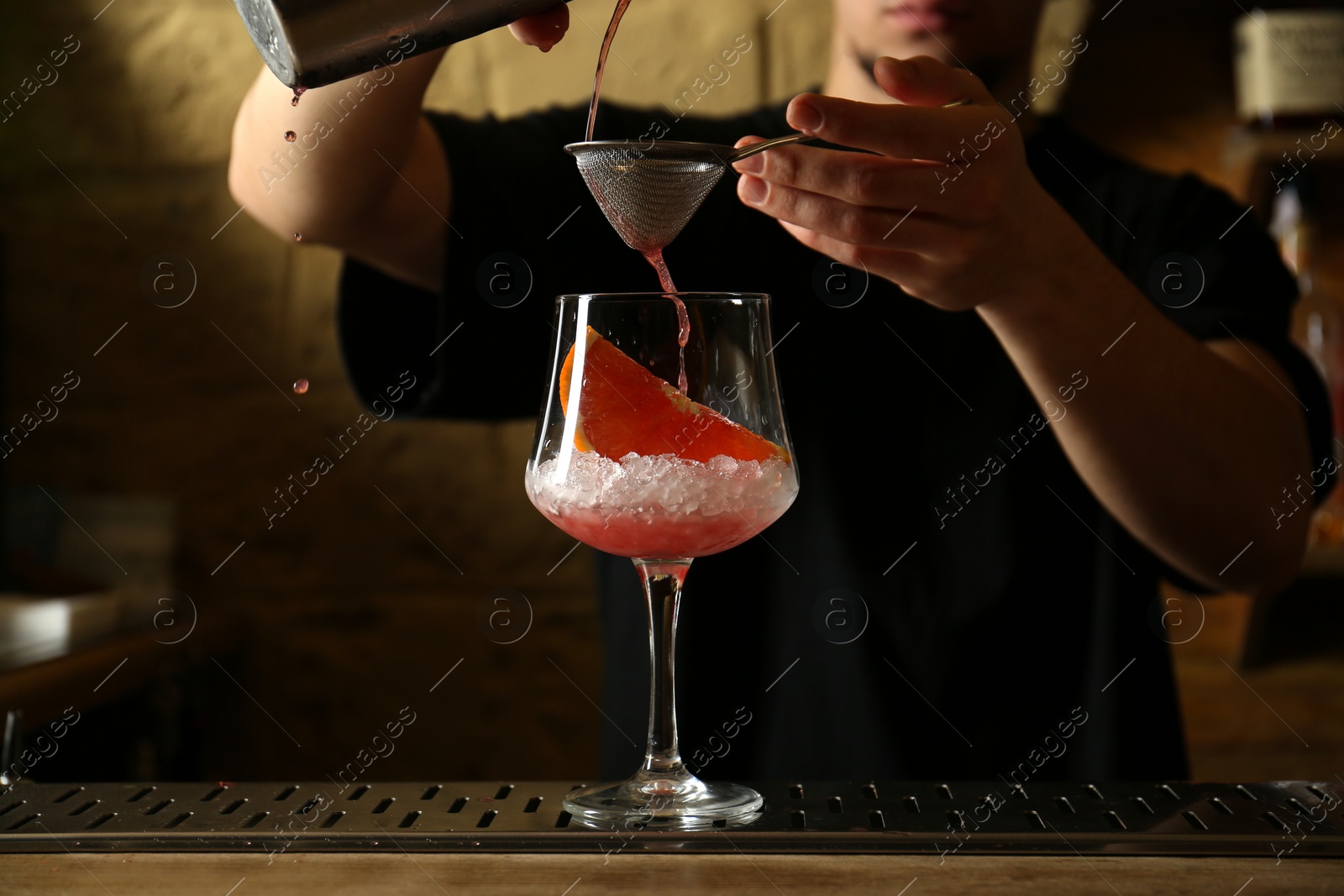 Photo of Bartender preparing fresh alcoholic cocktail at bar counter, closeup