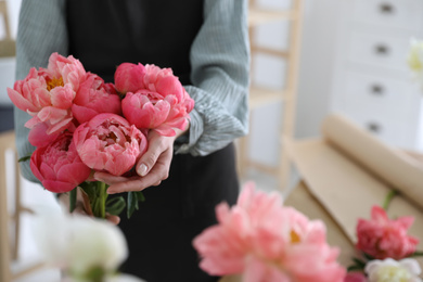 Photo of Florist with beautiful peony bouquet indoors, closeup