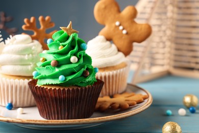 Tasty Christmas tree cupcake on light blue wooden table, closeup view. Space for text