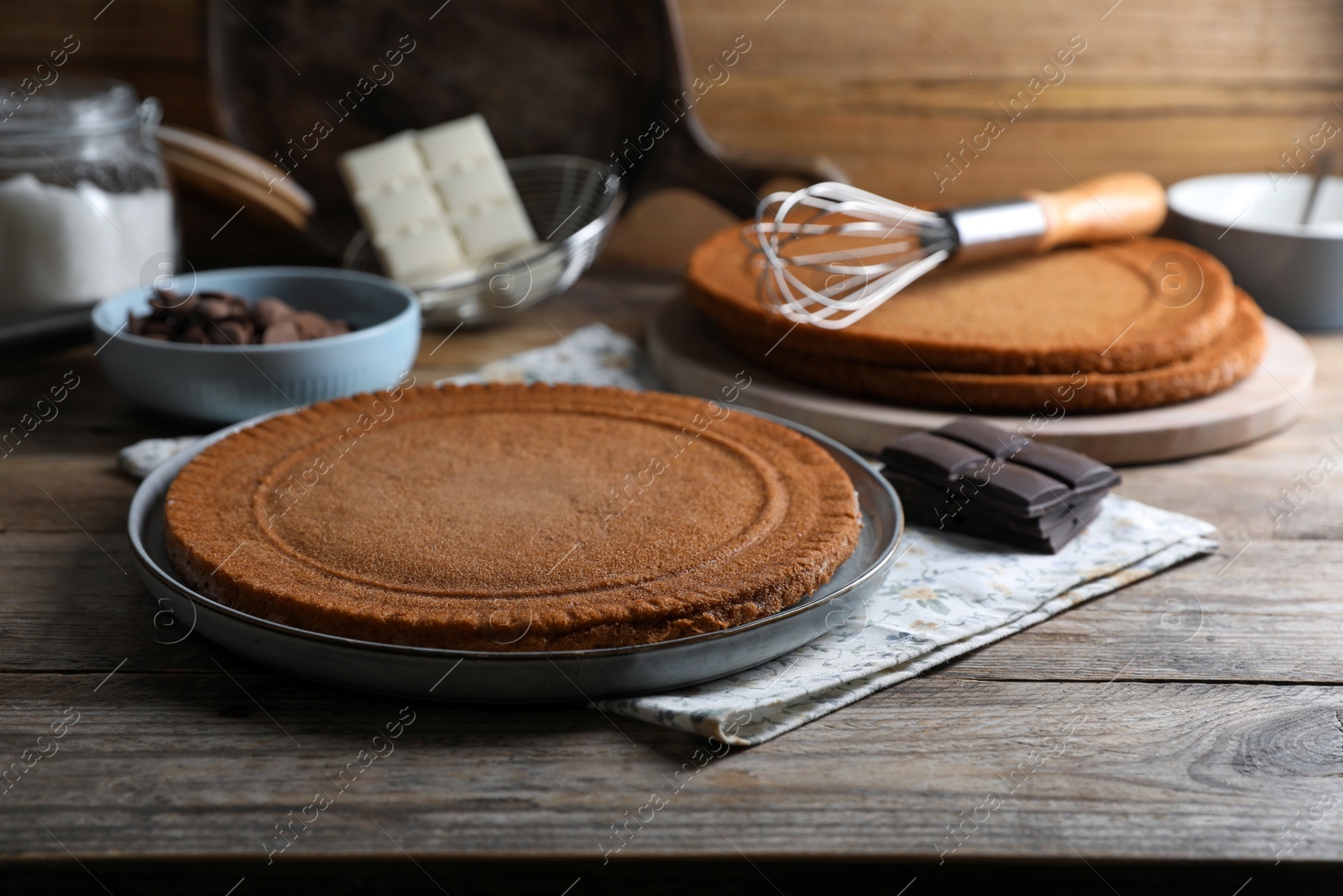 Photo of Delicious homemade sponge cake and ingredients on wooden table