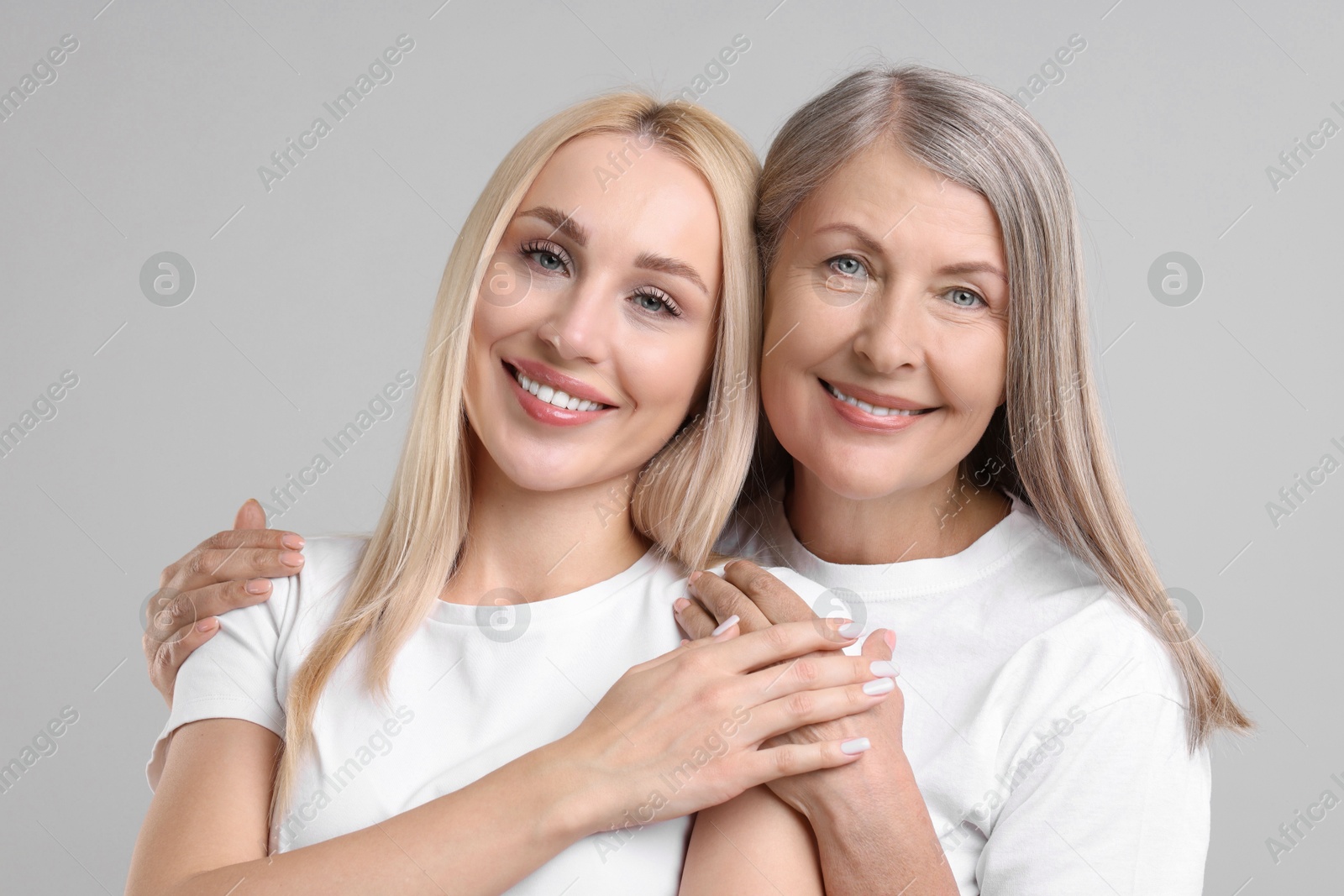 Photo of Family portrait of young woman and her mother on light grey background