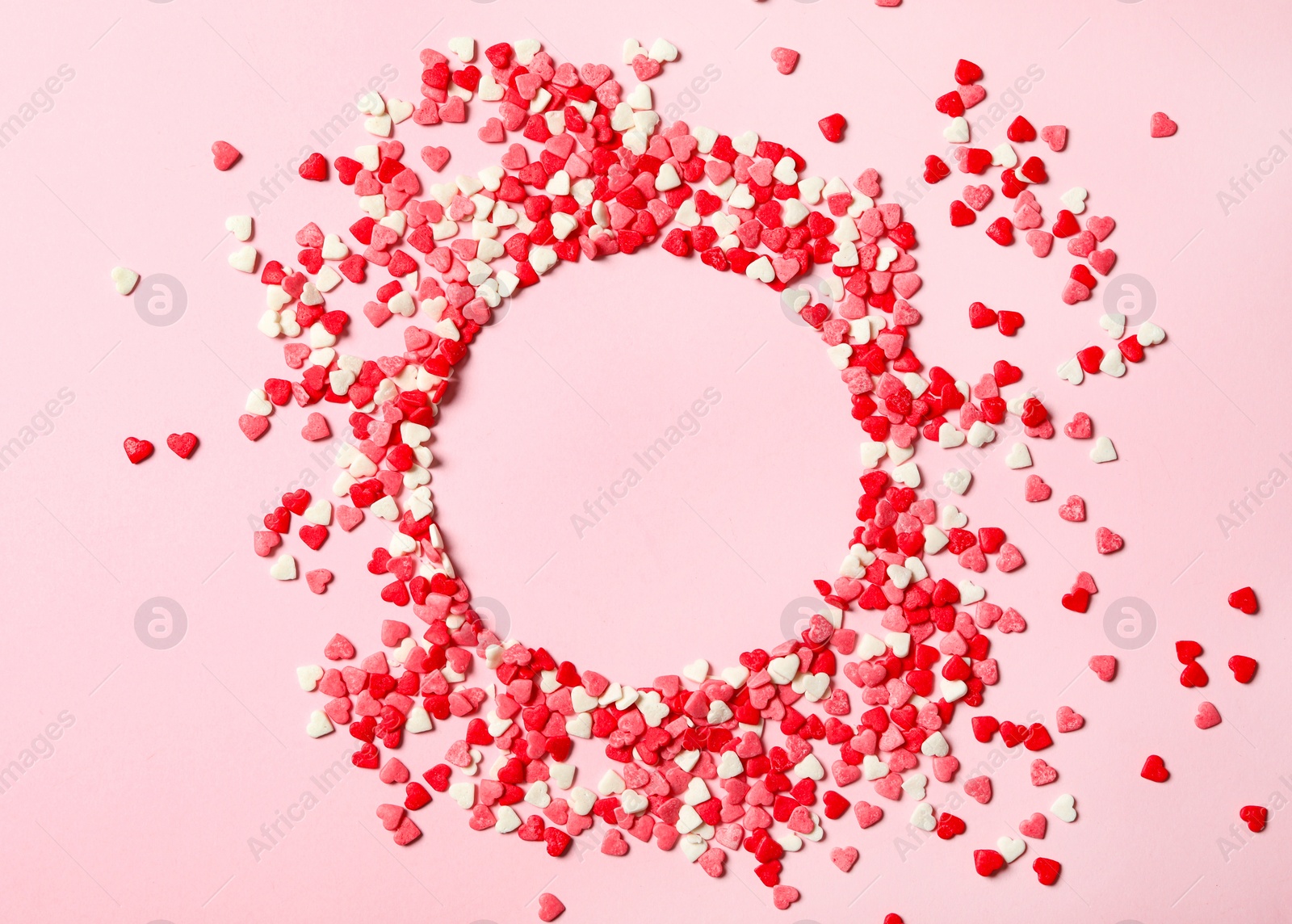 Photo of Frame made of heart shaped sprinkles on pink background, top view. Space for text