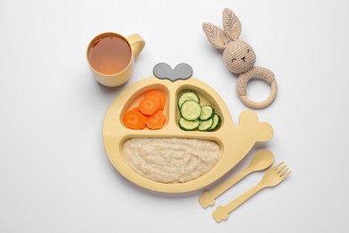 Photo of Healthy baby food in plate, cup with drink and toy on white background, top view