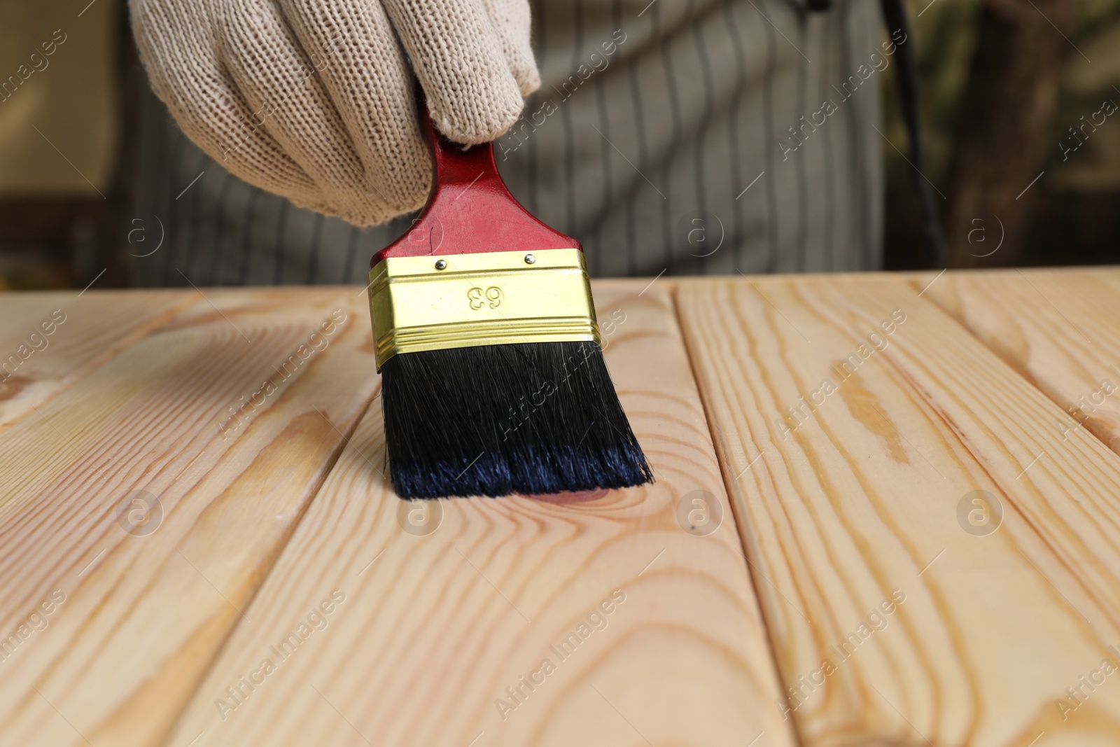 Photo of Man varnishing wooden surface with brush outdoors, closeup