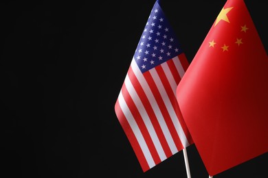 Photo of USA and China flags against black background, space for text. International relations