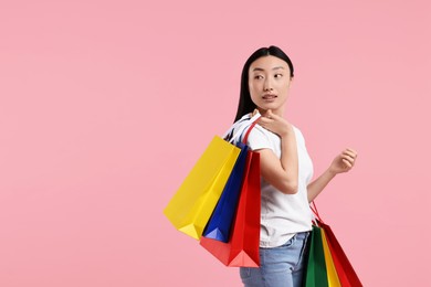 Photo of Beautiful woman with shopping bags on pink background. Space for text