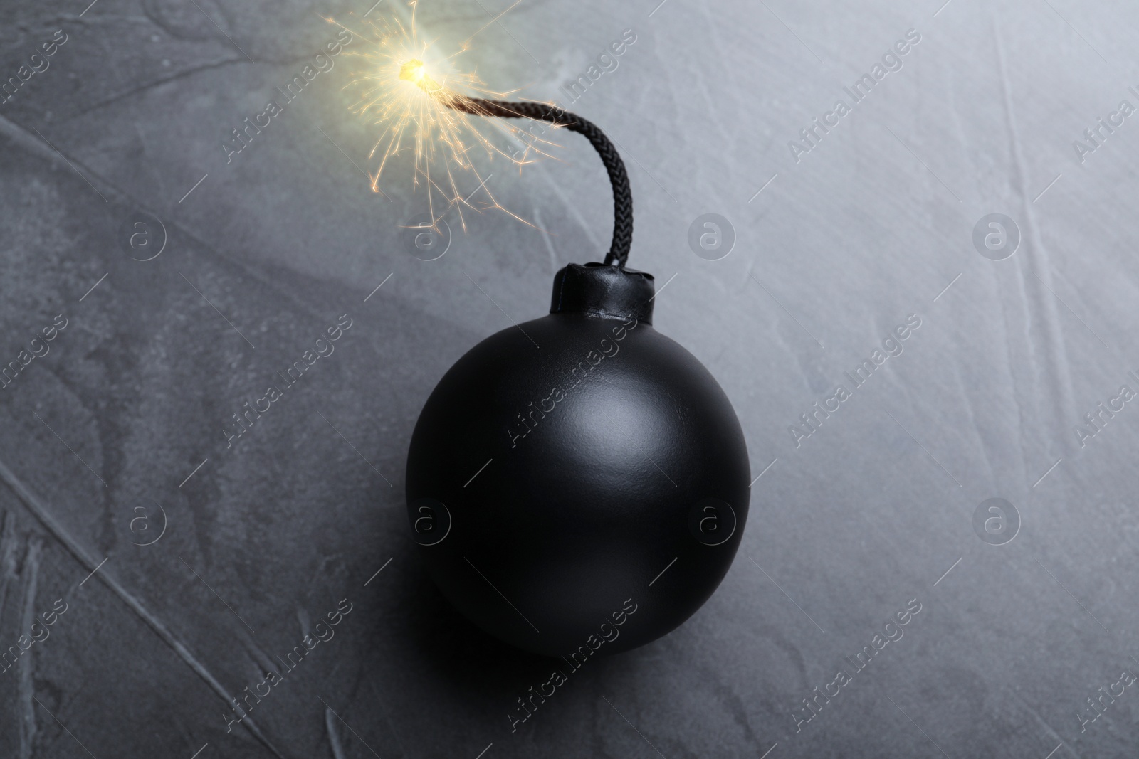 Image of Old fashioned black bomb with lit fuse on grey table, top view