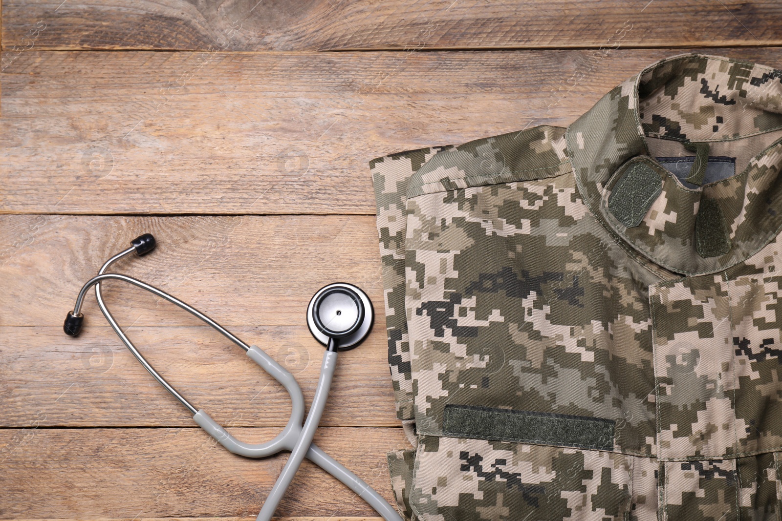 Photo of Stethoscope and military uniform on wooden background, flat lay