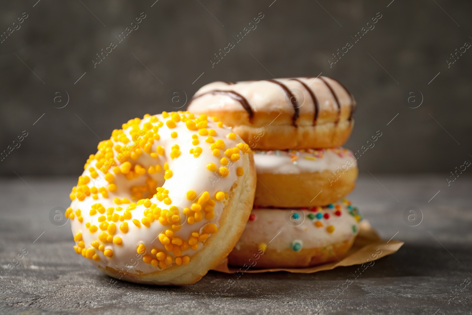 Photo of Sweet delicious glazed donuts on grey table