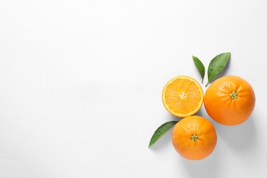 Photo of Juicy oranges and leaves on white background, top view