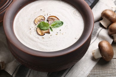Photo of Fresh homemade mushroom soup in ceramic pot on wooden table, closeup