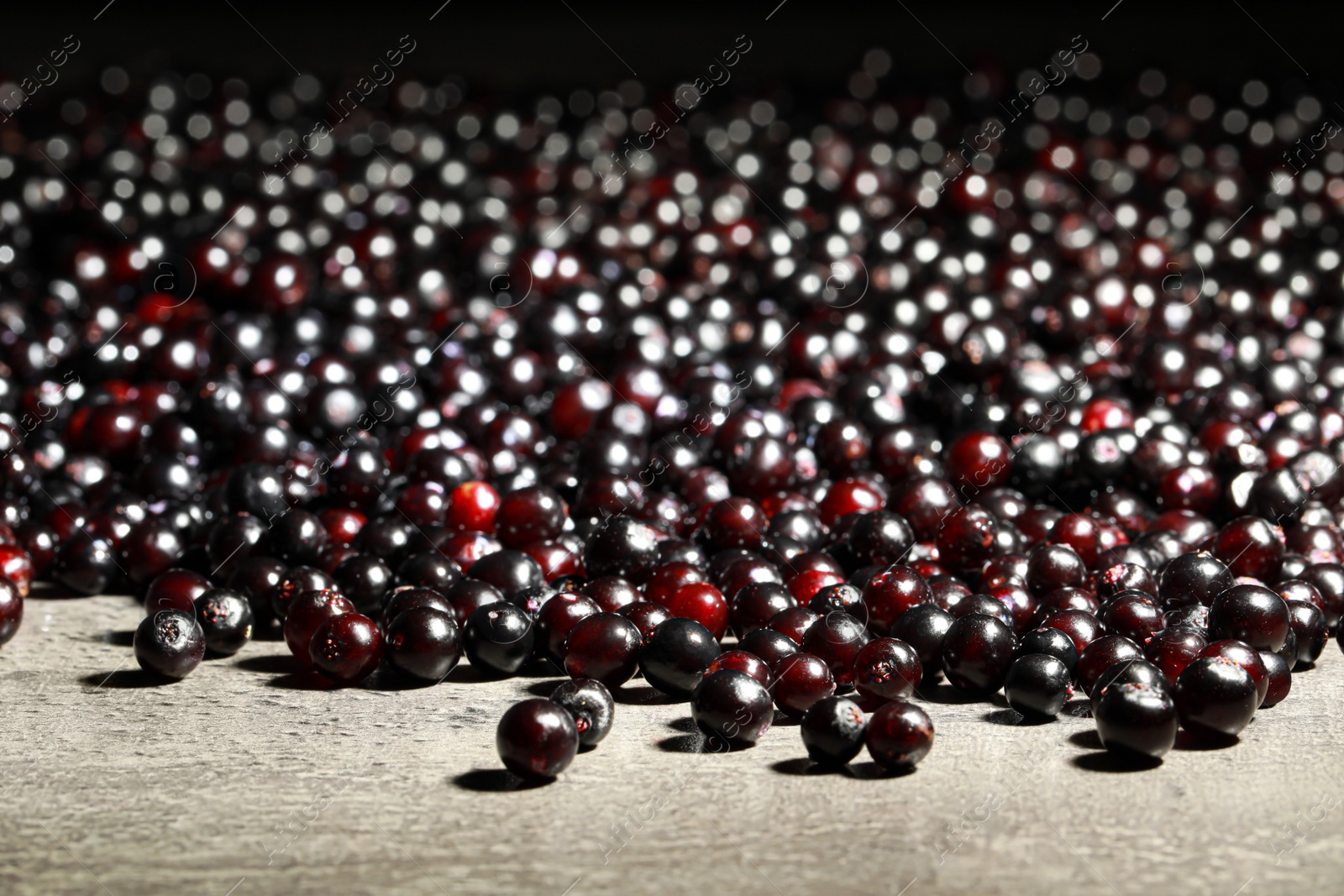 Photo of Many black elderberries (Sambucus) on grey table, closeup