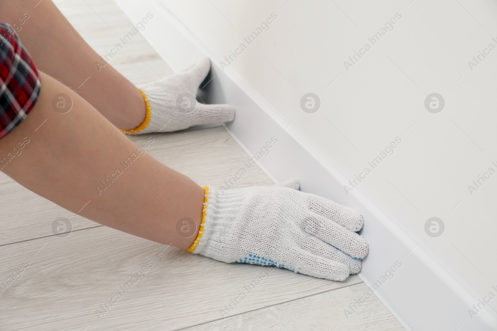 Photo of Man installing plinth on laminated floor in room, closeup