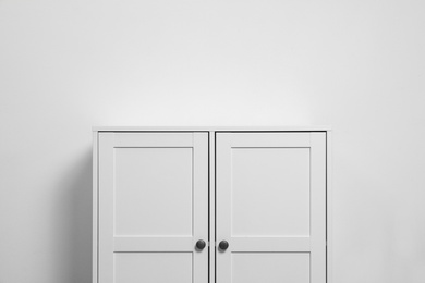 Wooden cabinet near white wall. Stylish home furniture