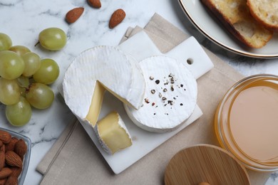 Flat lay composition with tasty brie cheese on white marble table