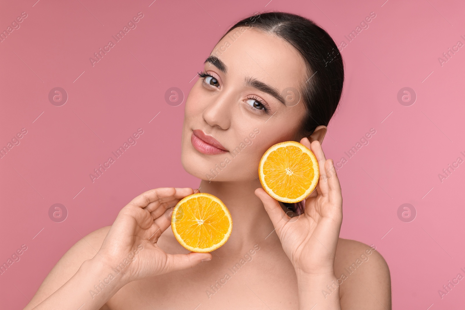 Photo of Beautiful young woman with pieces of orange on pink background